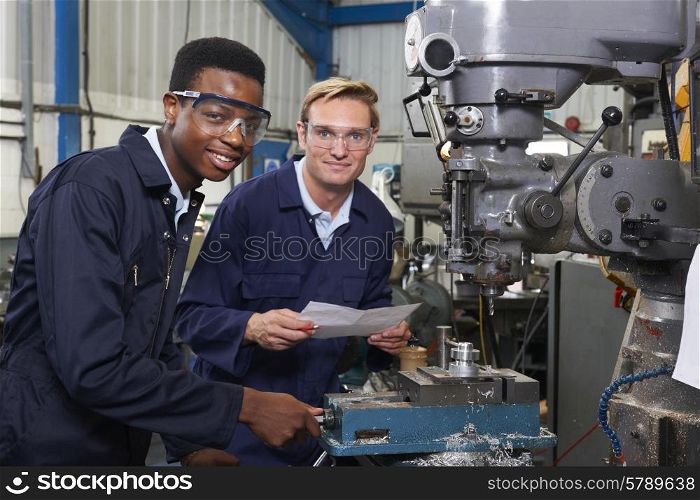 Engineer Showing Apprentice How to Use Drill In Factory