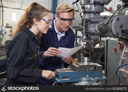 Engineer Showing Apprentice How to Use Drill In Factory