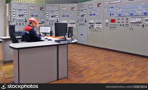 engineer sits and looks at monitor on main control panel of gas compressor station