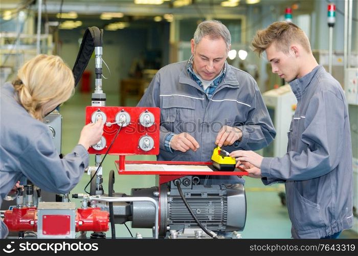 engineer training female and male apprentice on machine