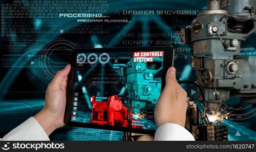 Engineer use augmented reality software in smart factory production line with automated application . Futuristic machinery in working in concept of Industry 4.0 or 4th industrial revolution.. Engineer use augmented reality software in smart factory production line