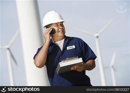 Engineer using mobile phone at wind farm