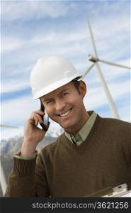 Engineer using mobile phone at wind farm, portrait