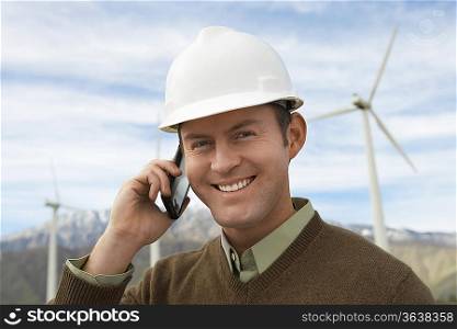 Engineer using mobile phone at wind farm, portrait