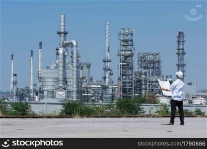 Engineer wearing white helmet standing on refinery background.. Engineer on refinery.