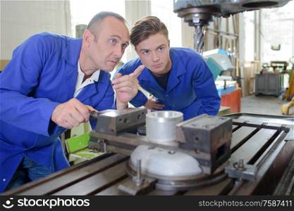 Engineer with apprentice pointing to machine