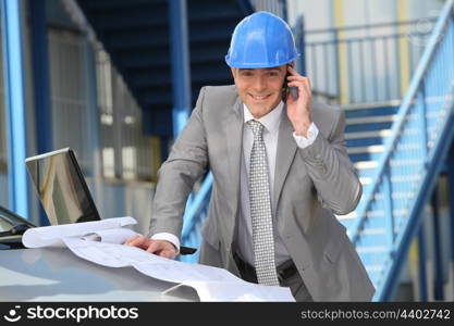Engineer with architectural plans and cellphone