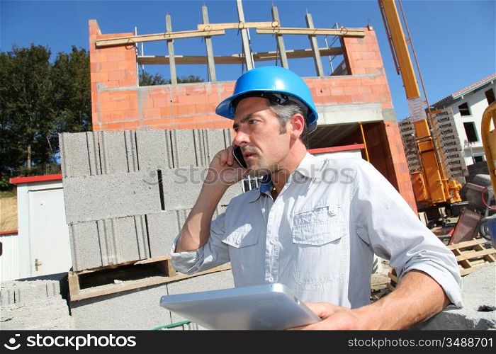Engineer with blue security helmet talking on mobile phone