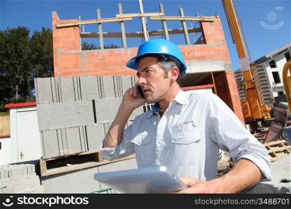 Engineer with blue security helmet talking on mobile phone