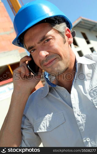 Engineer with blue security helmet talking on mobile phone