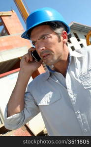 Engineer with blue security helmet talking on mobile phone