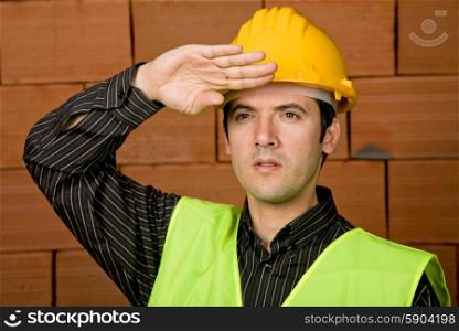 engineer with yellow hat with a brick wall as background