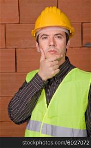 engineer with yellow hat with a brick wall as background