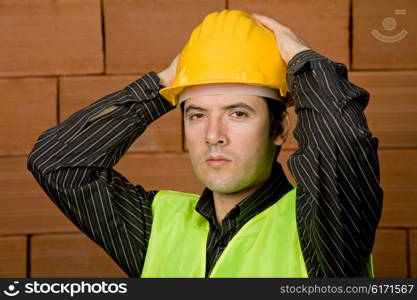 engineer with yellow hat with a brick wall as background