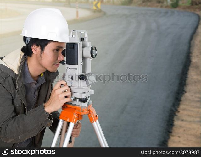 engineer working with survey equipment theodolite with road under construction background