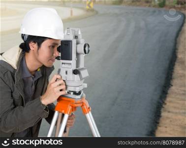 engineer working with survey equipment theodolite with road under construction background