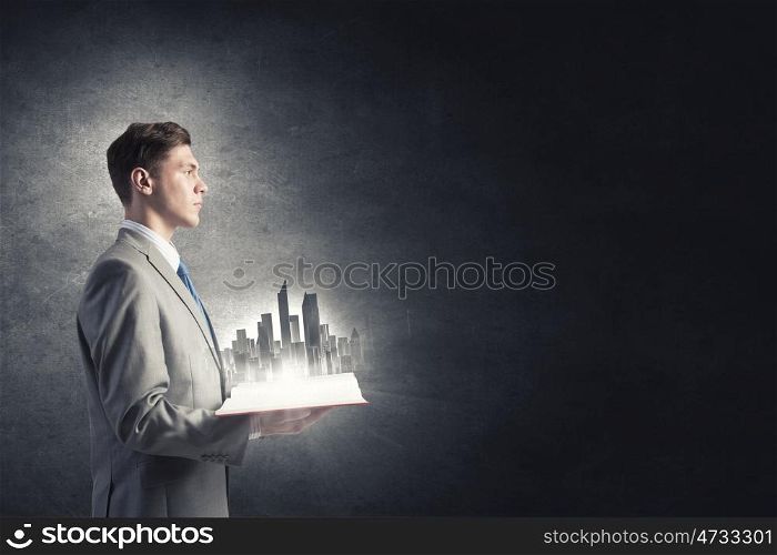 Engineering and construction. Businessman holding opened book with construction model on pages