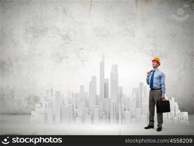 Engineering concept. Young businessman examining model of construction project