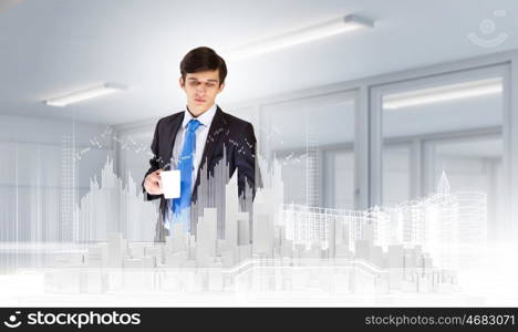 Engineering concept. Young businessman examining model of construction project