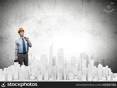 Engineering concept. Young businessman examining model of construction project