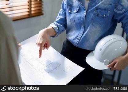 Engineering construction concept, Female engineer holding safety helmet and pointing on blueprint.