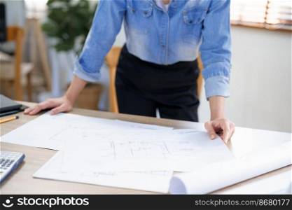 Engineering construction concept, Female engineer is checking blueprint of condominium in office.