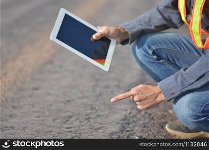 Engineering hold tablet is checking surface of road in the road construction area. Land transportation system