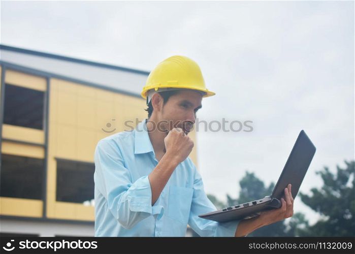 Engineering holding computer notebook with yellow hard hat working building construction estate