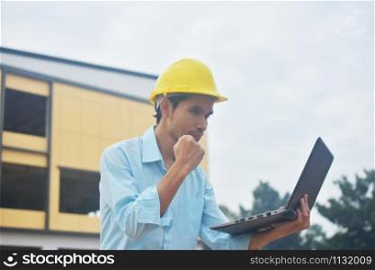 Engineering holding computer notebook with yellow hard hat working building construction estate