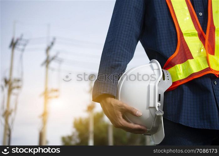 Engineering holds white safety hats and electric pole background