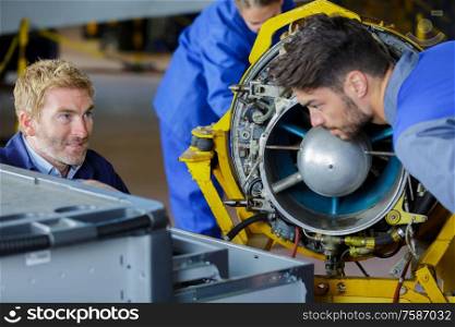 engineering teacher checking airplane engines with his students