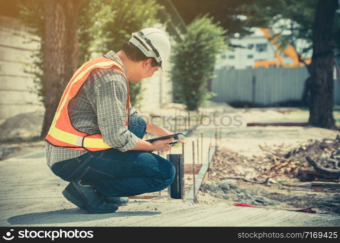 Engineering, wearing a helmet and holding tablets, sitting down To check the structure of the corridor in the park