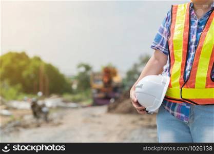 Engineering woman holding a white safety helmet standing In front of the construction site. Concepts for controlling and checking the construction accuracy