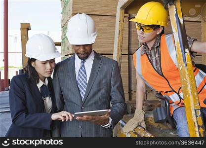 Engineers and female industrial worker looking at tablet PC