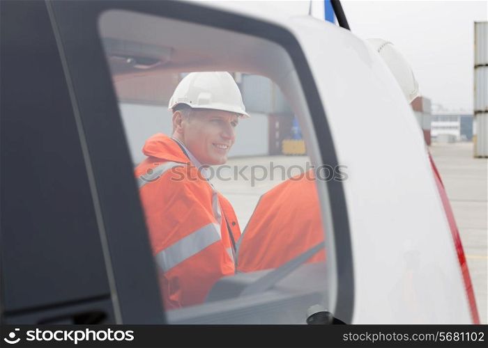 Engineers conversing beside car in shipping yard