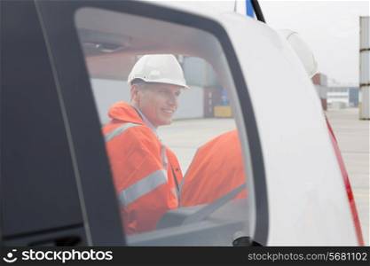 Engineers conversing beside car in shipping yard