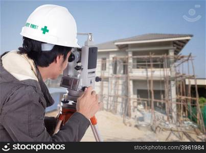 Engineers use tacheometer or theodolite with house construction site background