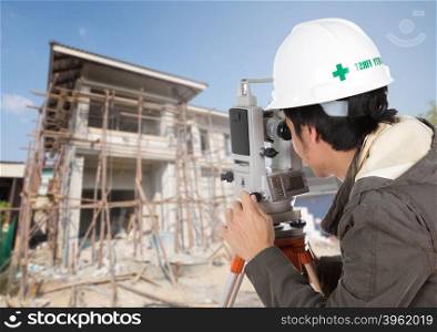 Engineers use tacheometer or theodolite with house construction site background