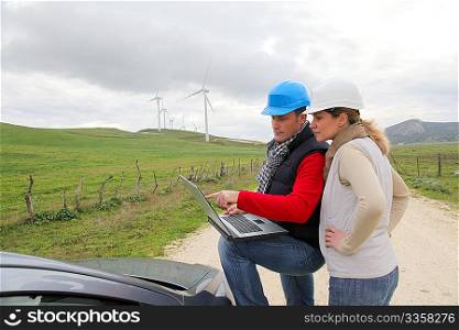 Engineers working by wind turbines field