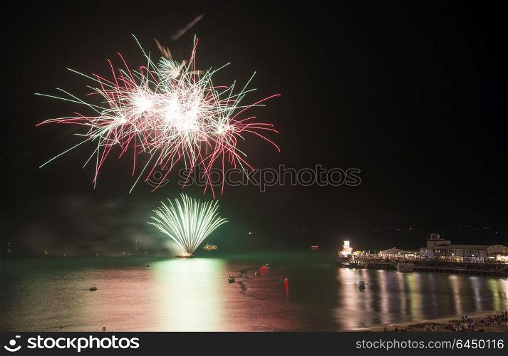 England, Dorset, Bournemouth. Firworks display over Bournemouth pier marking the end of Bournemouth Air Festival 2013.. Fireworks display over sea with pier and boats in water landscape scene