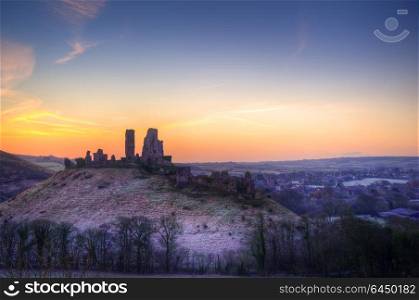 England, Dorset, Corfe Castle. Colourful sunrise over Corfe Castle.. Stunning Winter sunrise landscape over frosty Medieval castle on hill in countryside