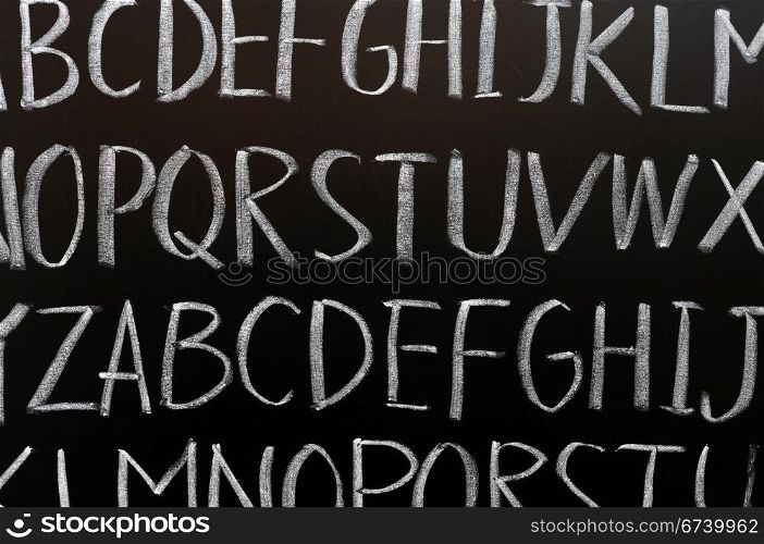 English alphabet background written with chalk on a blackboard