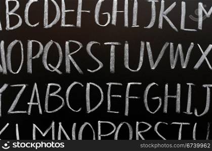 English alphabet background written with chalk on a blackboard