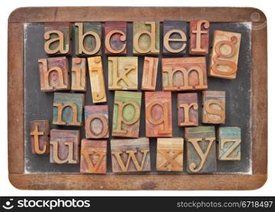 English alphabet in vintage letterpress wood type on an old slate blackboard