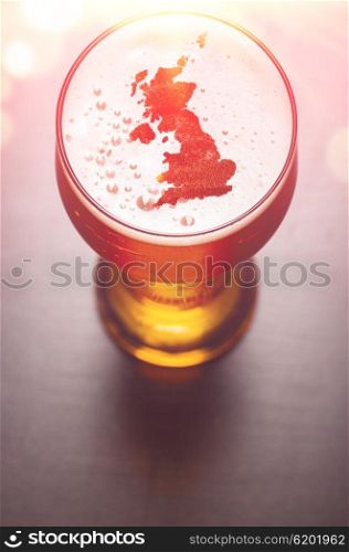 English beer concept, Great Britain silhouette on foam in beer glass on black table. The continents shapes are altered ones from visibleearth.nasa.gov