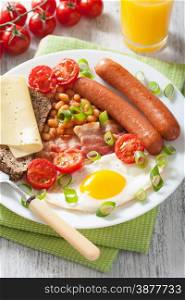 english breakfast with fried egg sausages bacon tomatoes beans