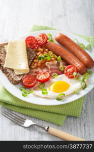 english breakfast with fried egg sausages bacon tomatoes beans