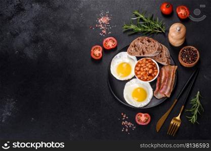English breakfast with fried eggs, bacon, beans, tomatoes, sπces and herbs. A hearty and nutritious start of the day. English breakfast with fried eggs, bacon, beans, tomatoes, sπces and herbs