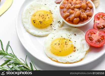 English breakfast with fried eggs, bacon, beans, tomatoes, spices and herbs. A hearty and nutritious start of the day. English breakfast with fried eggs, bacon, beans, tomatoes, spices and herbs