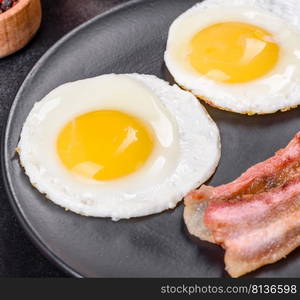 English breakfast with fried eggs, bacon, beans, tomatoes, spices and herbs. A hearty and nutritious start of the day. English breakfast with fried eggs, bacon, beans, tomatoes, spices and herbs